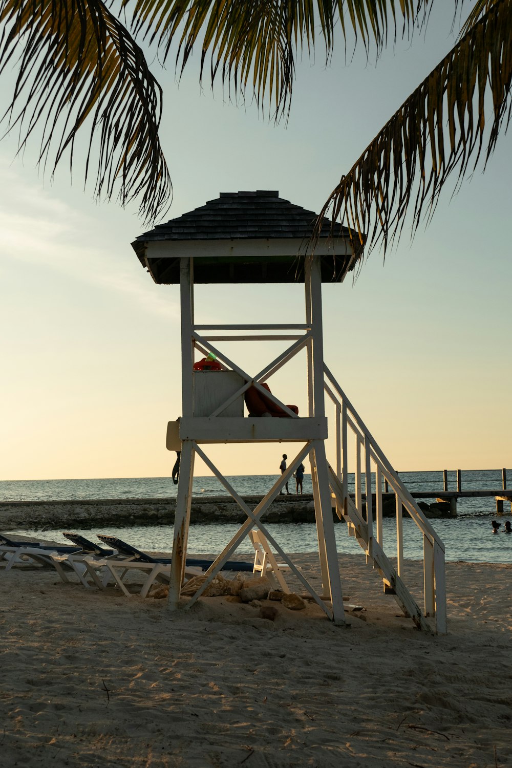 a lifeguard chair sitting on the beach under a palm tree