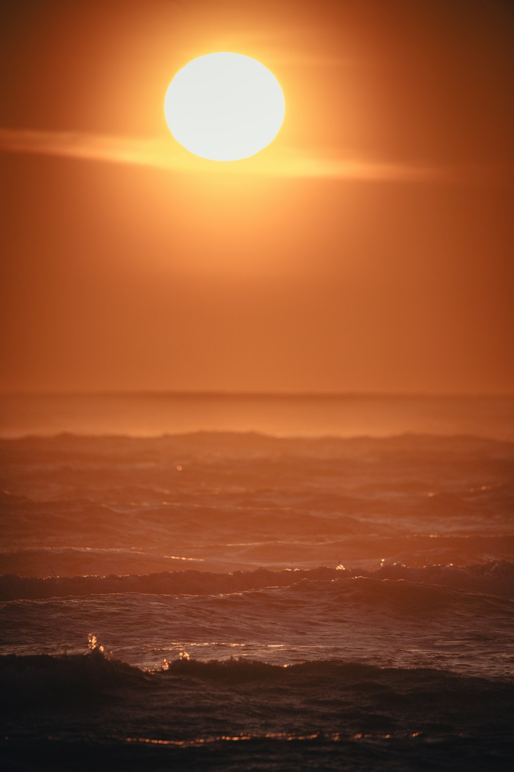 the sun is setting over the ocean with waves