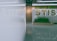 A modern indoor space features a sign with the letters 'STIS'. The area includes a decorative panel with indoor plants and greenery. A reflection on the glossy floor adds to the sleek, contemporary aesthetic.