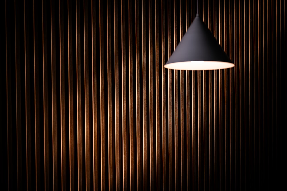 a black lamp hanging from a wooden wall