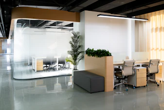 A sleek modular office setup with glass walls and modern furnishings in a bright, open space.