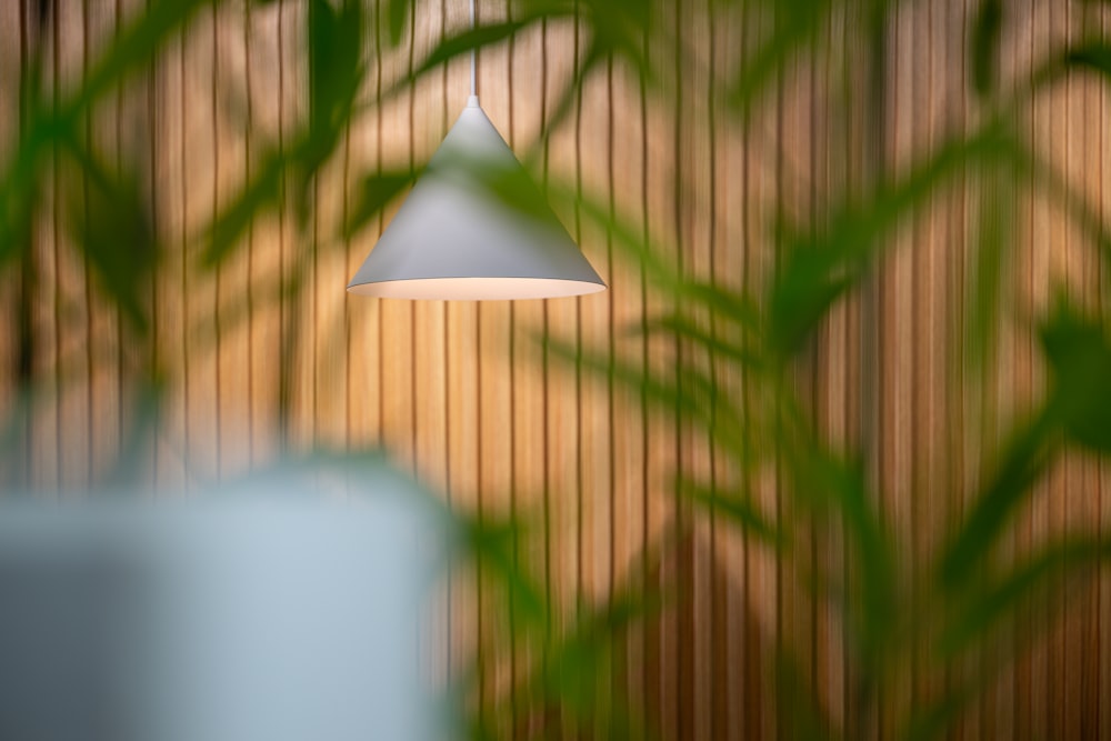 a white light hanging from a ceiling next to a plant