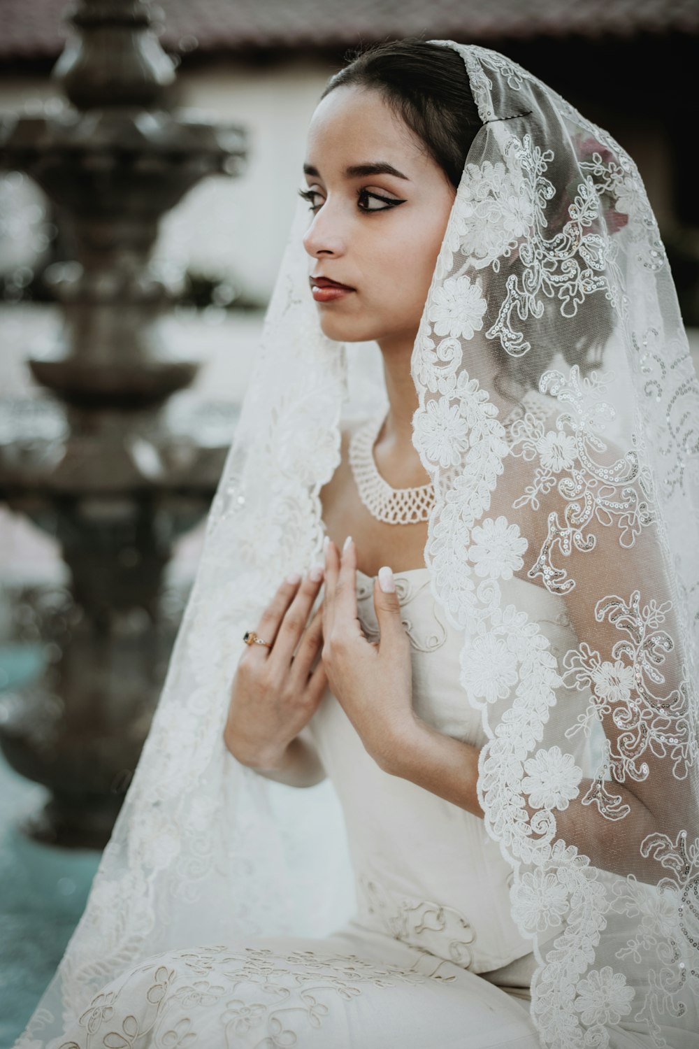 a woman in a wedding dress sitting in front of a fountain