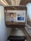The photo features a screen in an airplane, displaying flight information from Emirates airline for flight EK225 from Dubai to San Francisco in seat 14K. The screen interface offers options like information, communication, and entertainment. Advertisements and travel details, including a map and promotional offers, are visible. The surroundings exhibit luxury finishes with wood paneling.