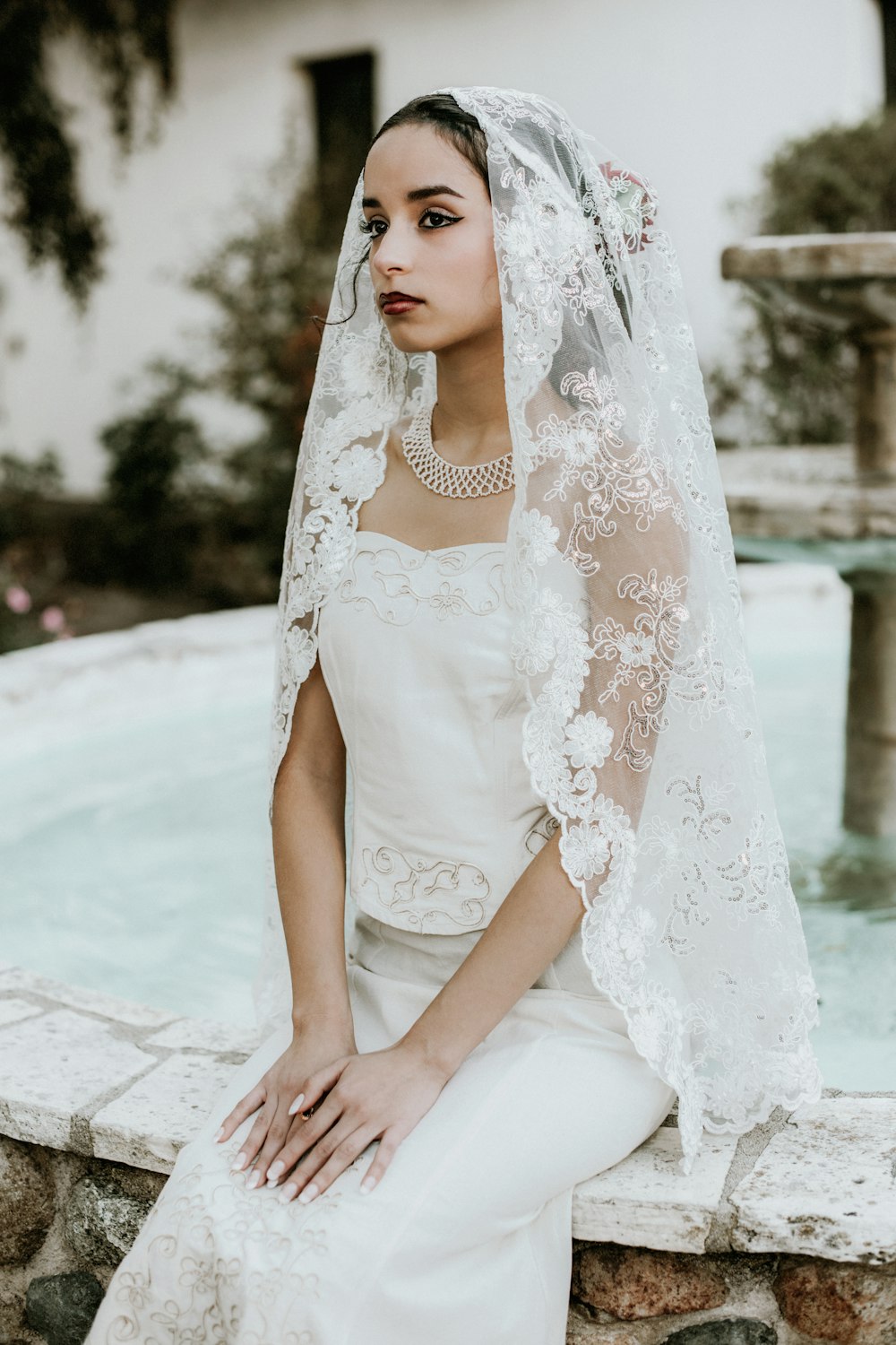 a woman in a wedding dress sitting on a ledge