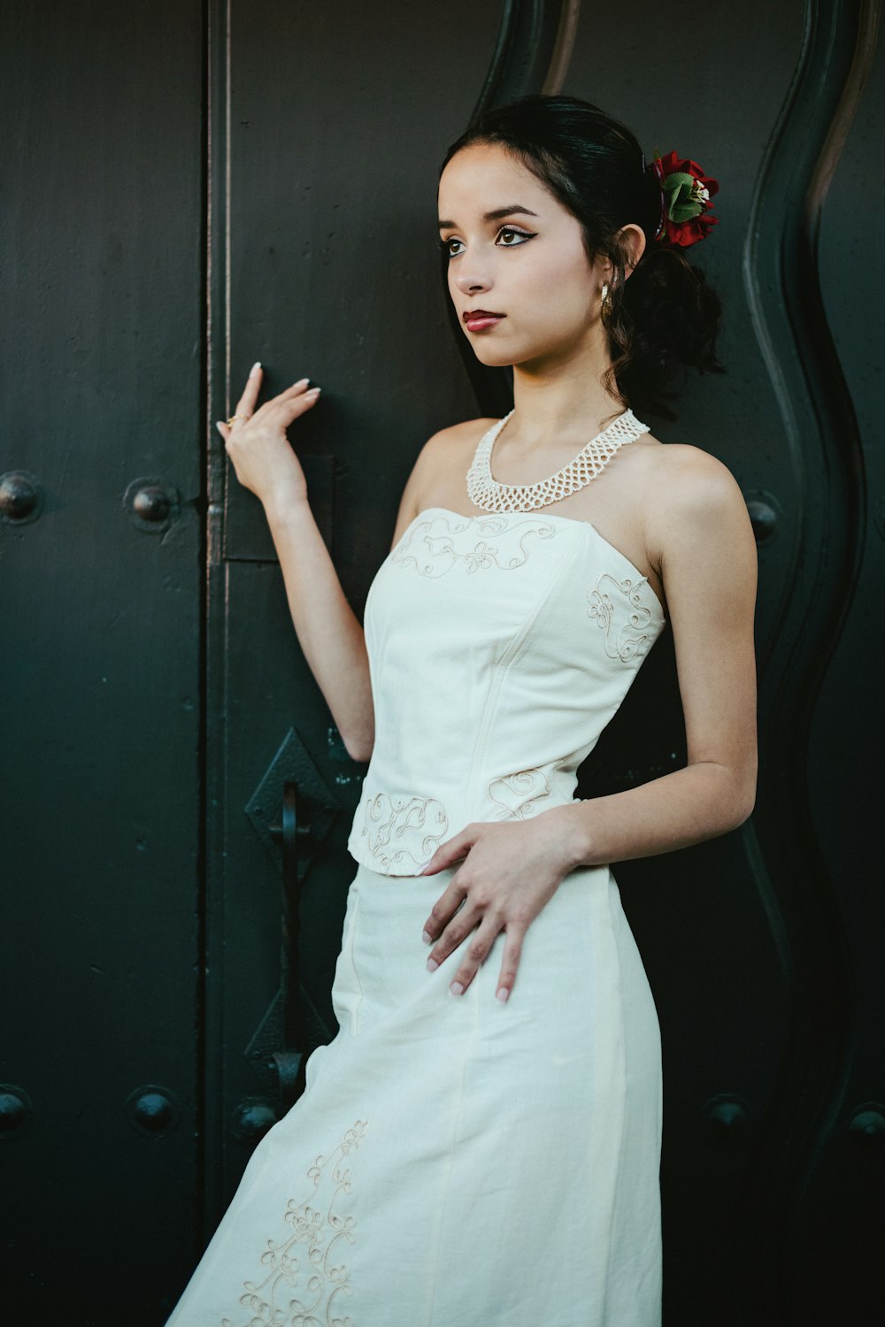 a woman in a white dress leaning against a black door