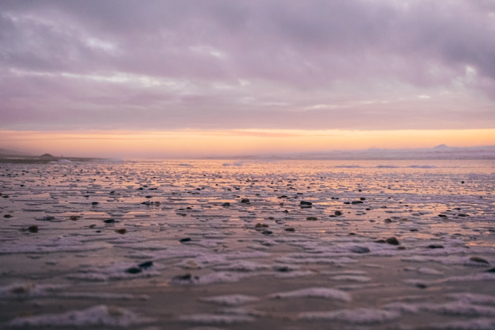 a view of a beach at sunset from the shore