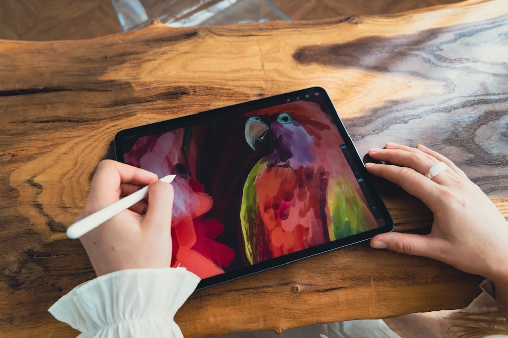 a person is drawing on a tablet with a pencil