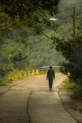 A thoughtful figure walking along a quiet roadside at dawn, deep in contemplation of the universe.