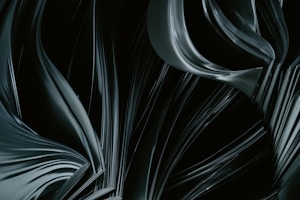 Dark, flowing shapes create a sense of movement and texture, resembling abstract fabric or liquid in shadowy tones.