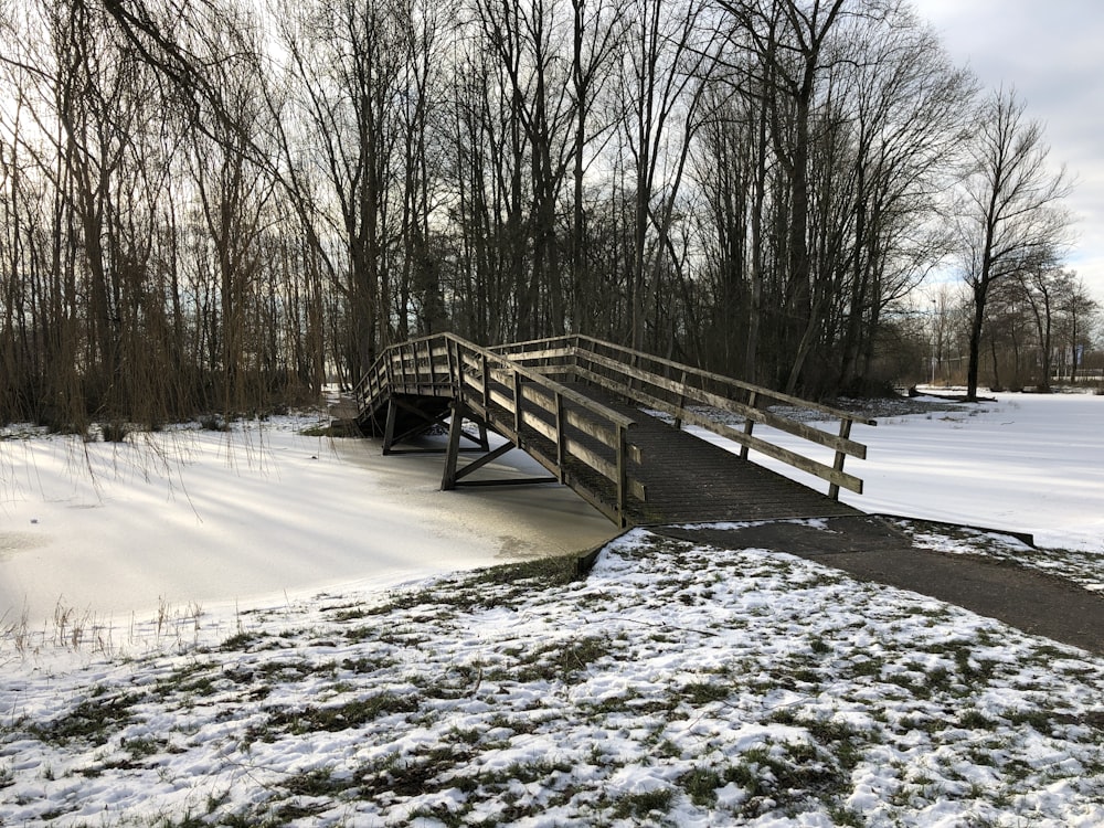 a wooden bridge over a snow covered river