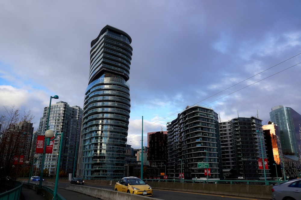 a yellow car driving down a street next to tall buildings