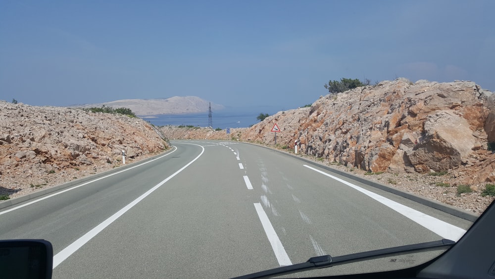 a car driving down a road next to a large rock formation