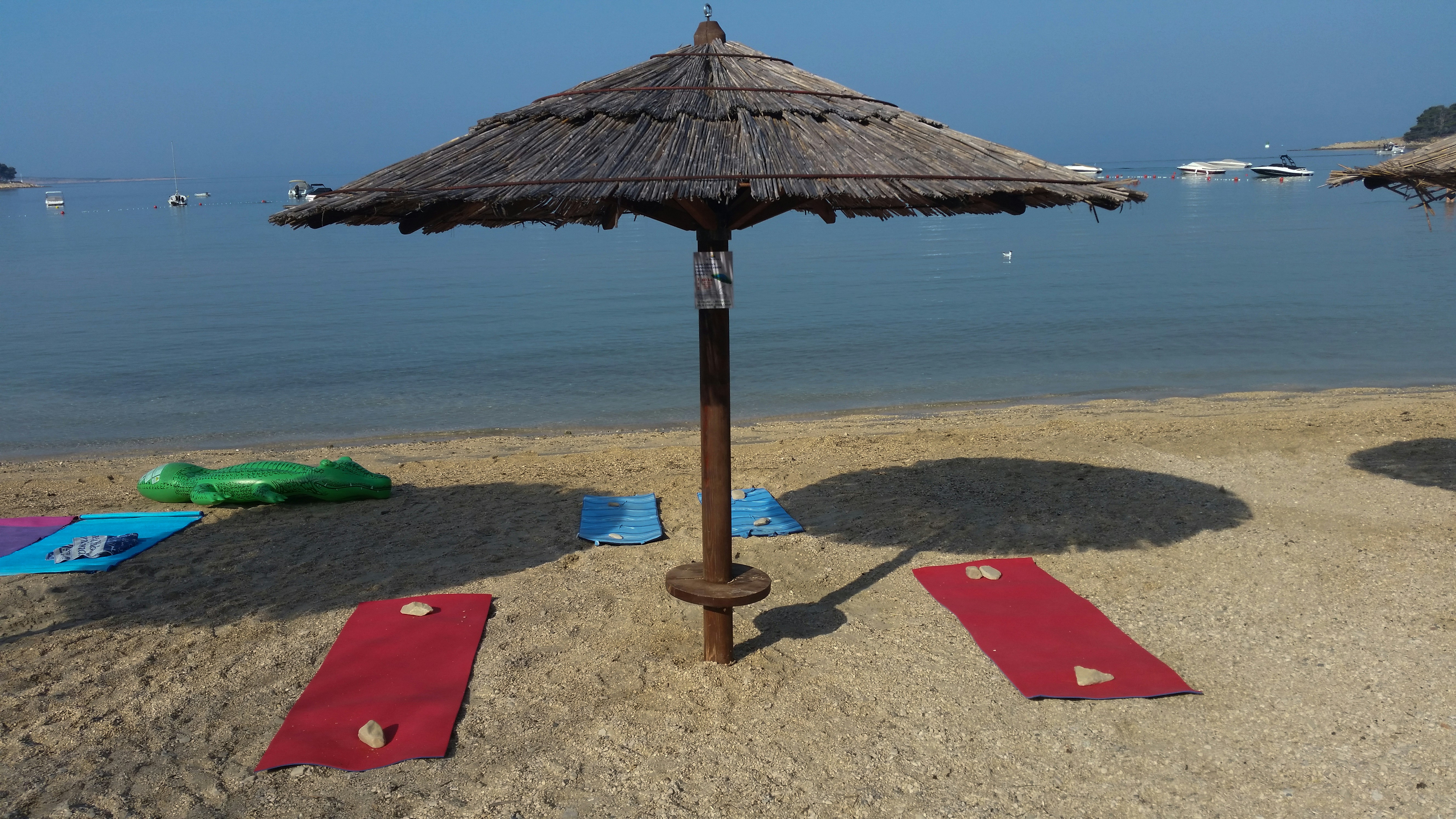 A beach with a straw umbrella and red mats photo – Free Beach Image on ...