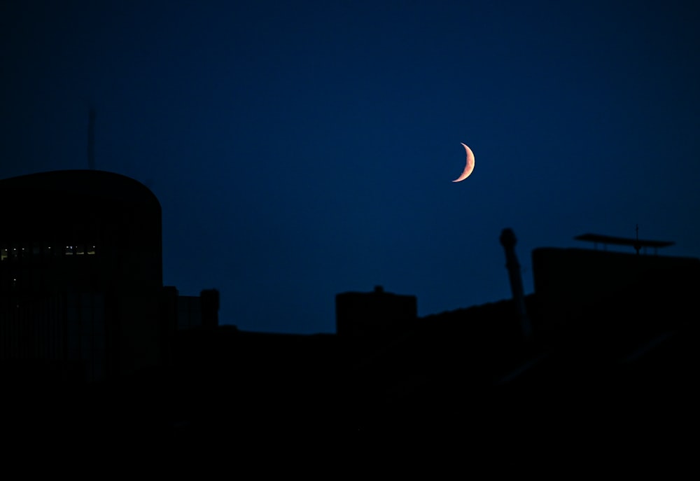 a half moon is seen in the sky over a city