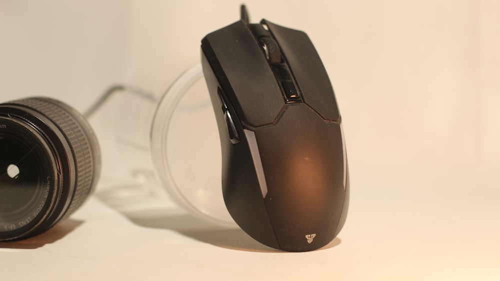 Un mouse de computadora sentado junto a la lente de una cámara
