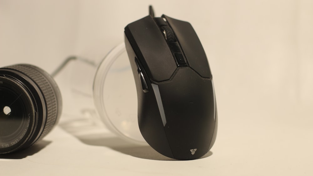 il mouse di un computer seduto accanto all'obiettivo di una fotocamera
