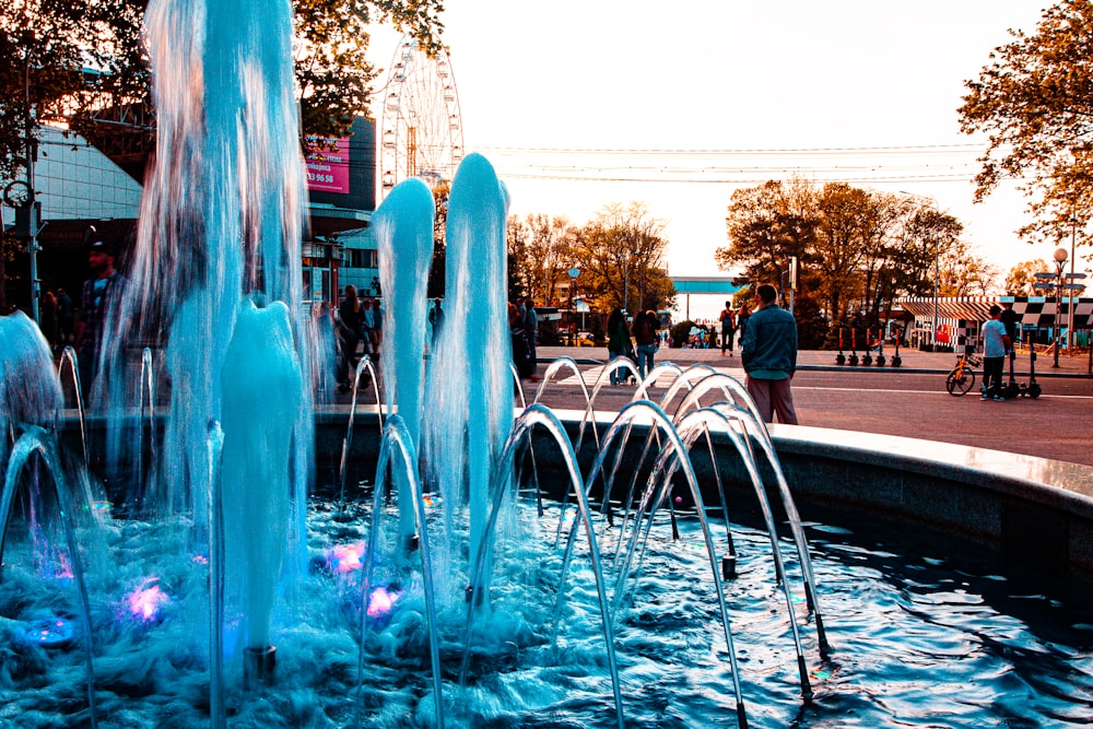 a group of people standing around a water fountain