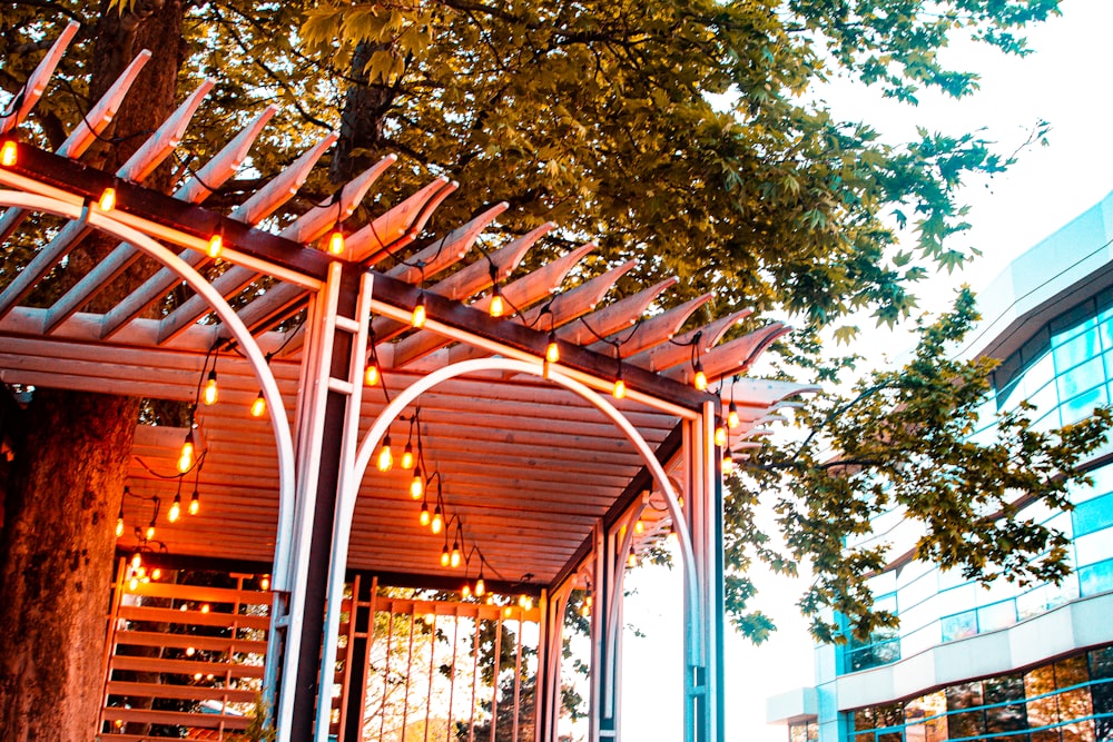 a wooden gazebo with lights hanging from it's sides