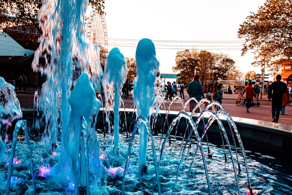 a group of people walking around a water fountain