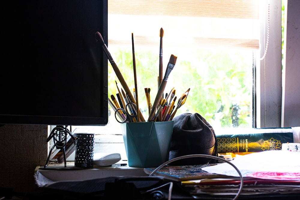 a desk with a computer monitor and a bunch of pens