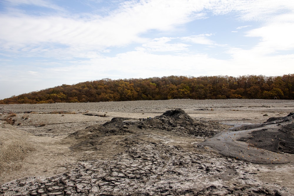 a dirt field with a hill in the background