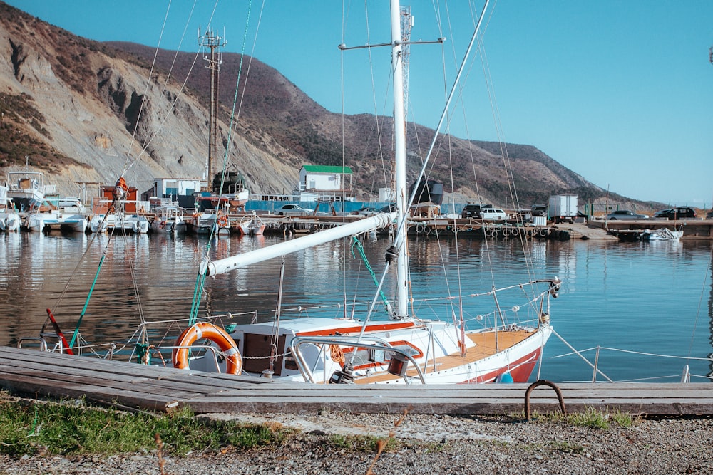 a sailboat docked in a harbor with mountains in the background