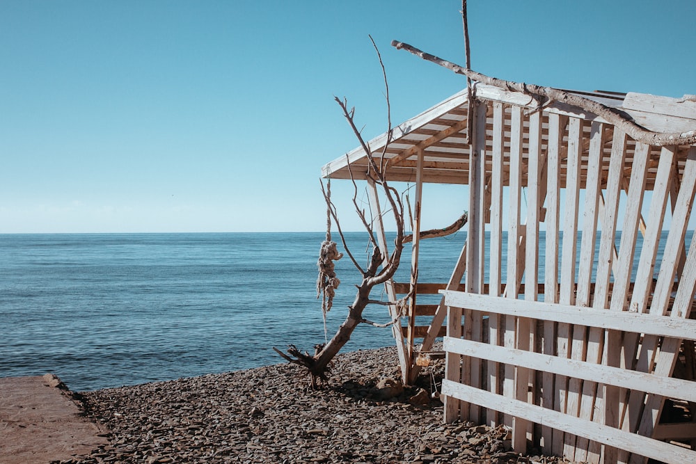 a wooden structure sitting on top of a beach next to the ocean