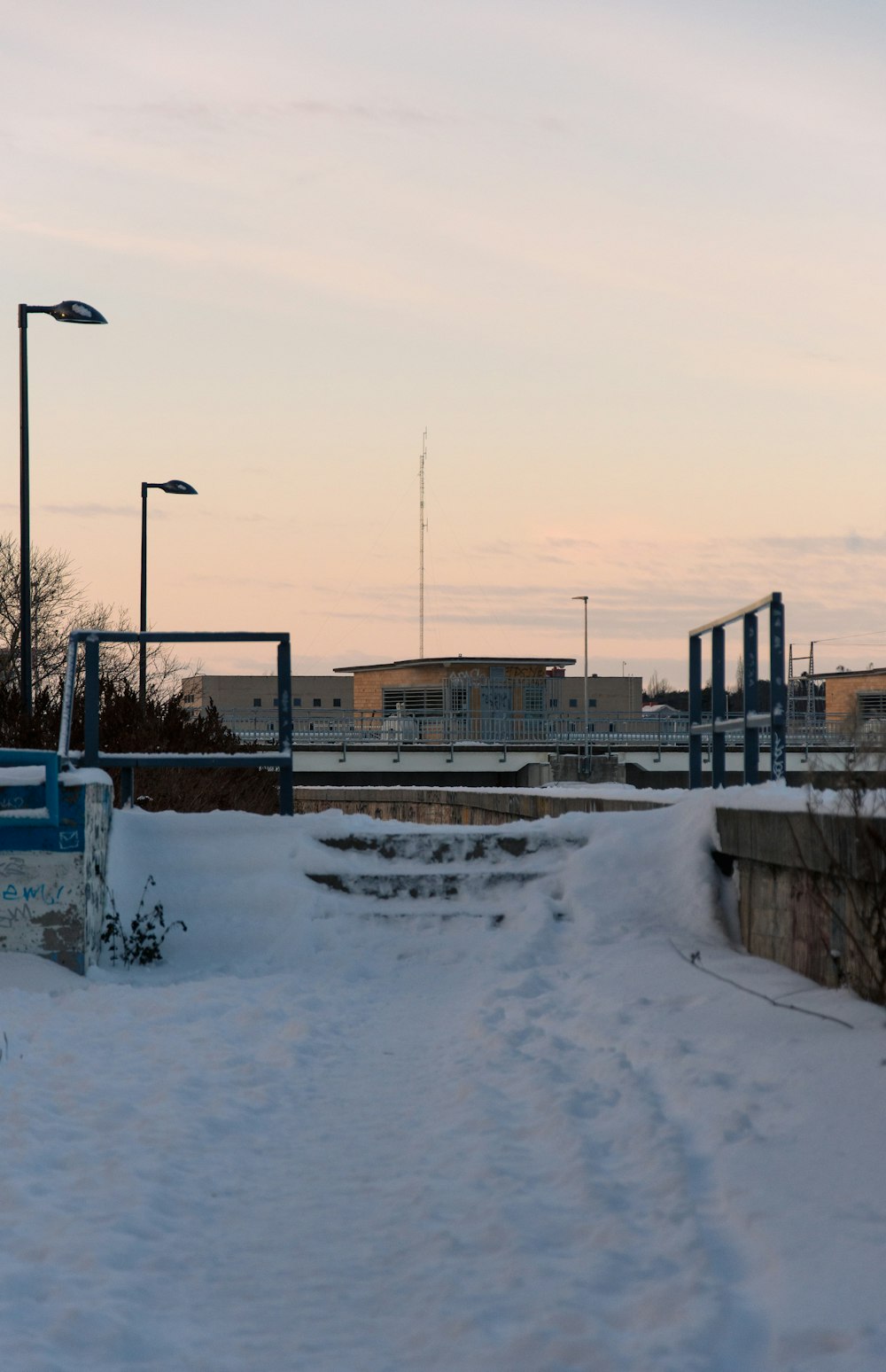 a snow covered path with a light pole in the background