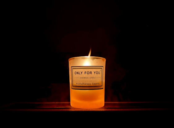 A warm, glowing candle with a custom label featuring a Bible verse, set against a cozy wooden background.