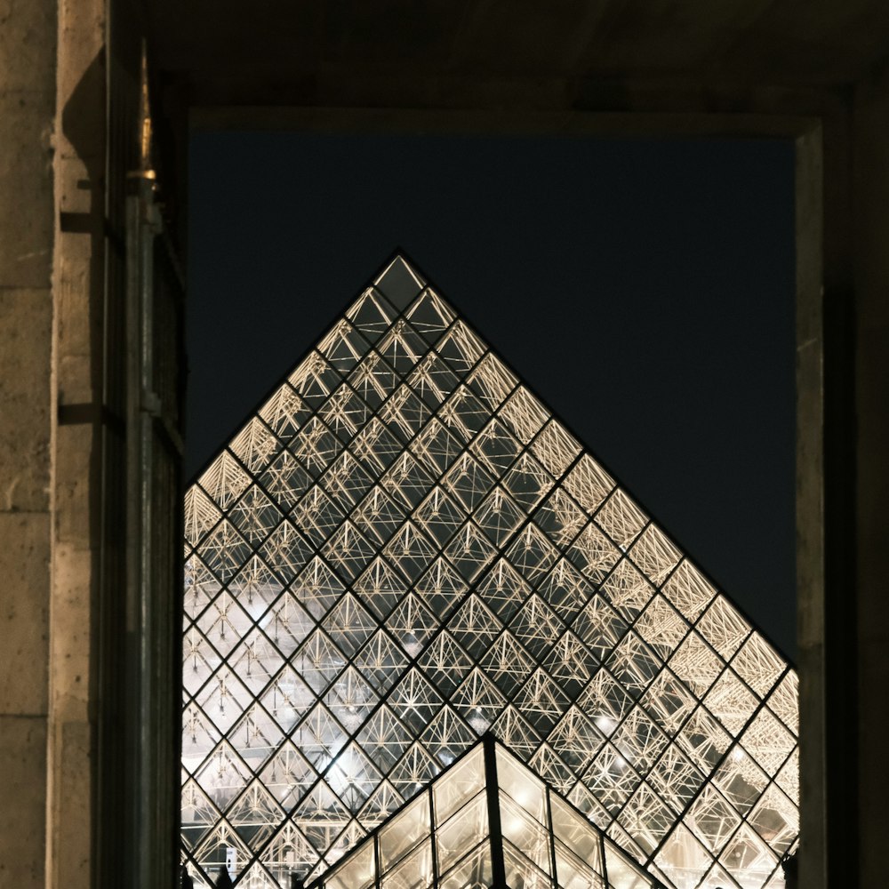 a very tall glass pyramid with a clock on it's side