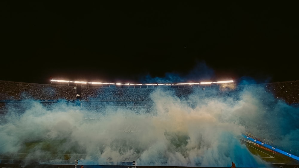 a stadium filled with lots of smoke on top of a field