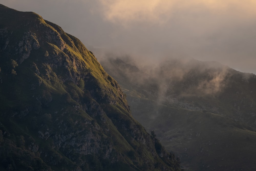 a mountain covered in green grass and clouds