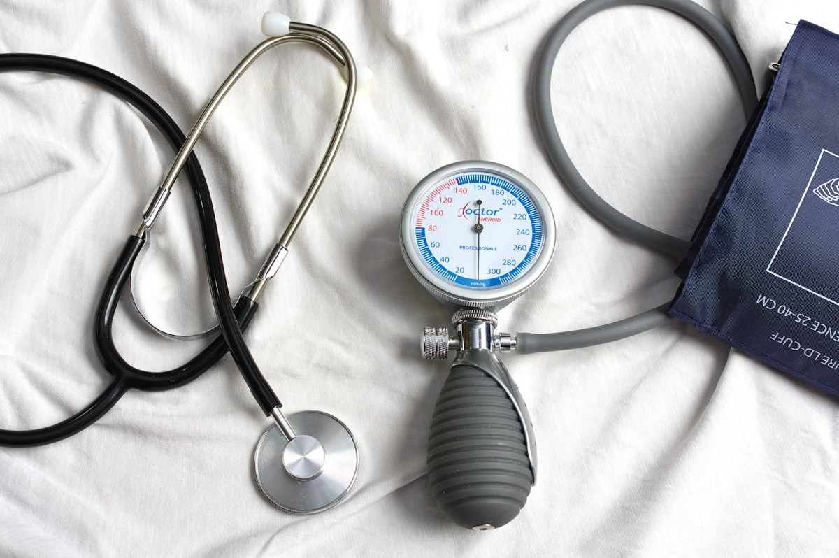A stethoscope laying on top of a bed next to a medical bag in a clinical setting