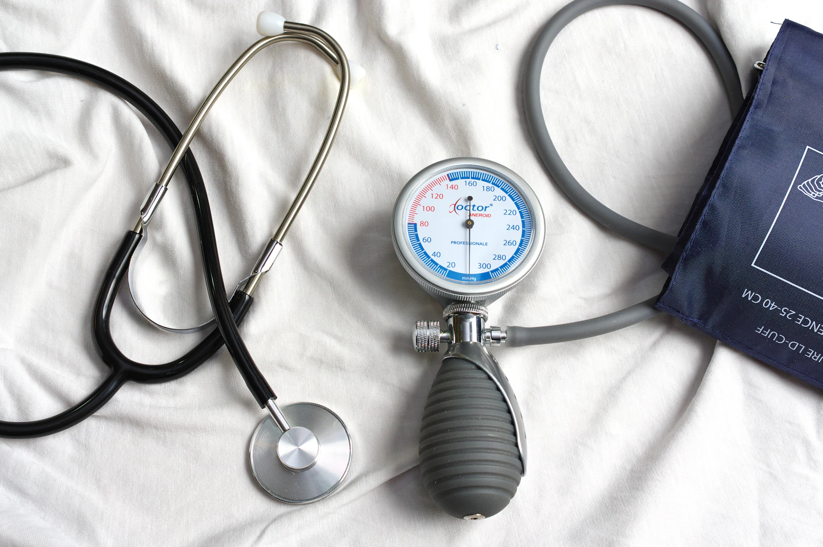 A stethoscope and blood pressure cuff laid on a bed