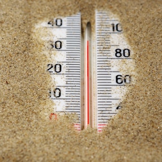 a close up of a thermometer in the sand
