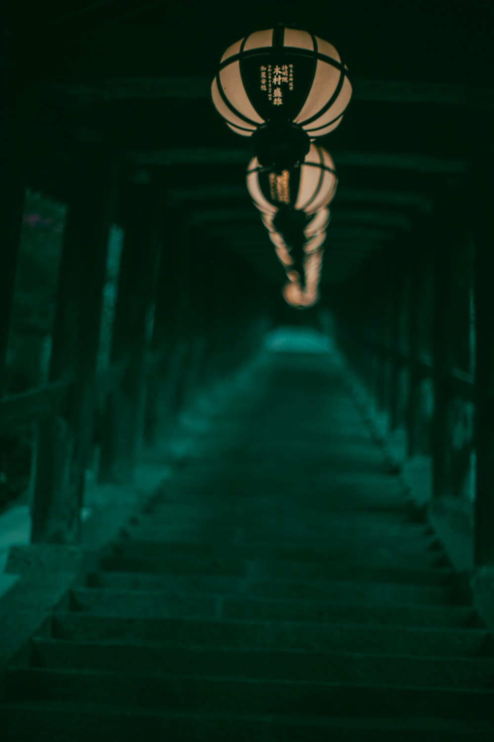 a dark hallway with stairs and a lantern hanging from the ceiling