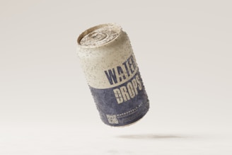 A weathered aluminum can labeled 'WATER DROPS' appears to be floating against a neutral background. The surface of the can is speckled with dirt, giving it a rustic and aged appearance.