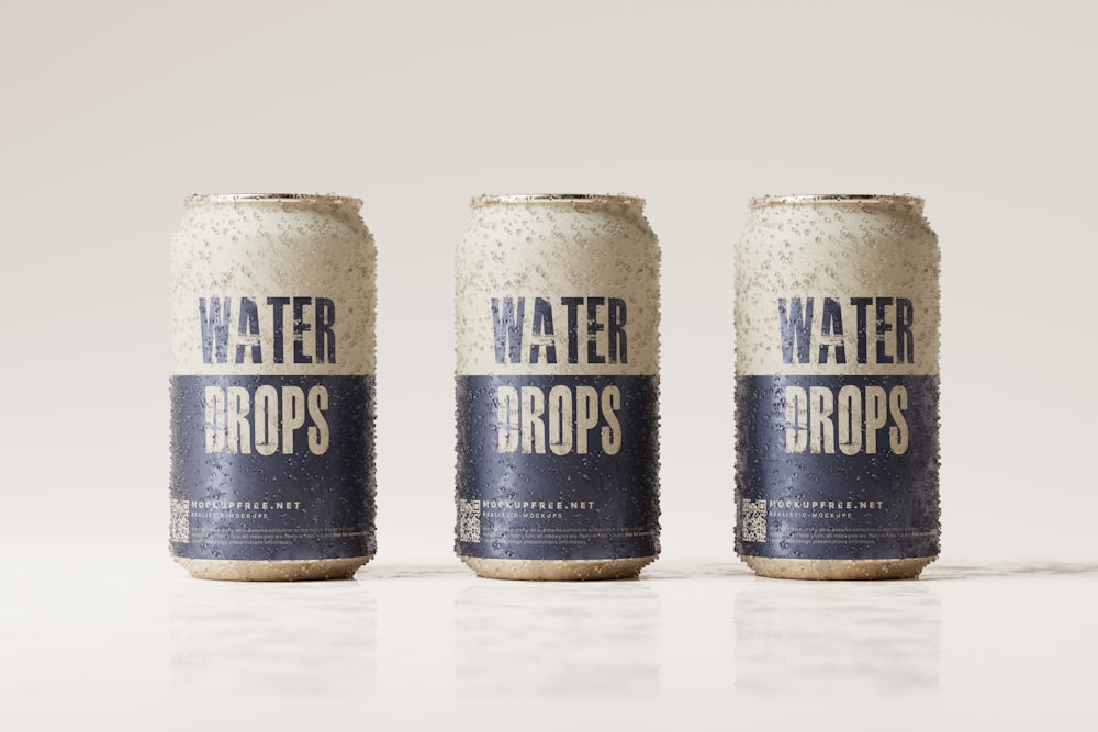 three cans of water drops on a white surface