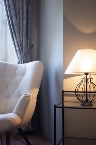 A cozy living room corner featuring a plush velvet armchair with a sleek side table adorned with a brass lamp.