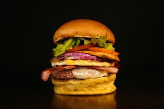 A gourmet burger stacked high with melted cheese, crispy bacon, and fresh lettuce on a toasted bun.