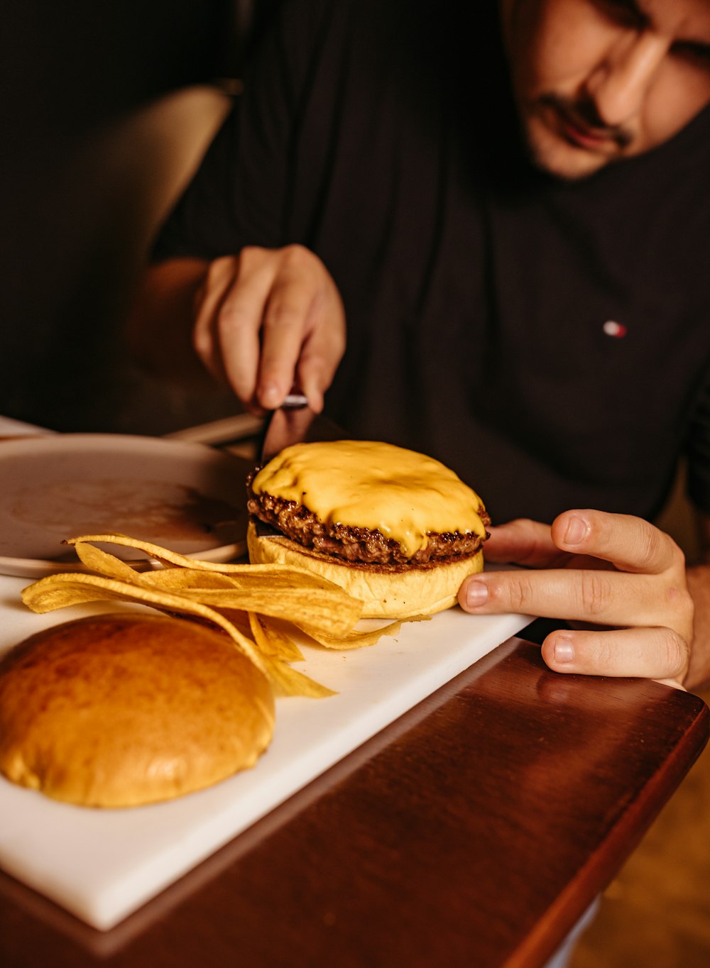 a man sitting at a table cutting into a sandwich