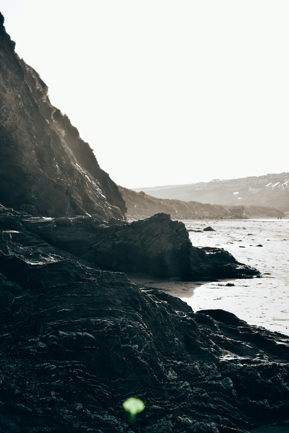 a person standing on a rocky beach next to the ocean