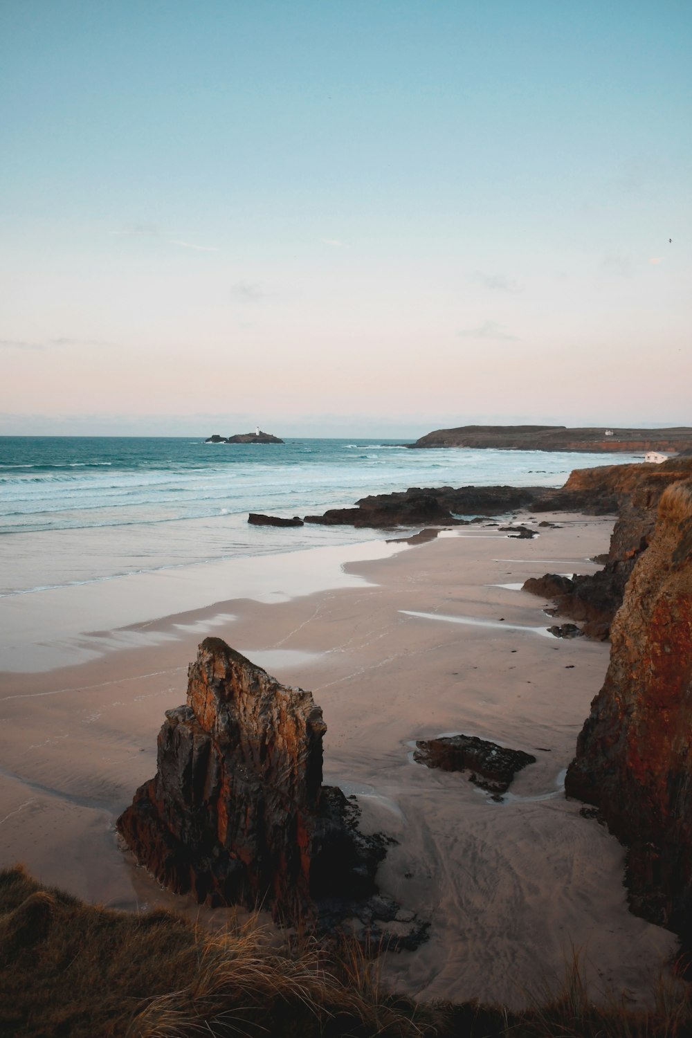 a beach with a rock outcropping in the sand