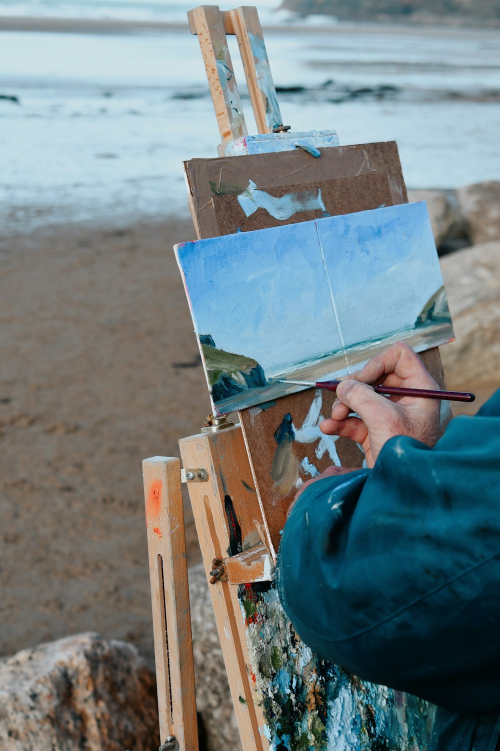 a person is painting on an easel on the beach