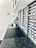 A sleek, modern workspace with a long black countertop. Numerous labeled compartments are neatly organized along the wall, possibly for filing or storage purposes. The setting includes some decorative elements like a small plant arrangement, creating a minimalistic and organized vibe.