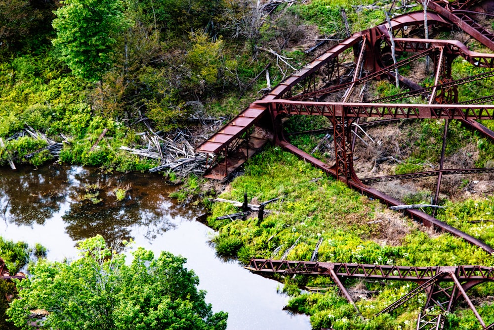 a rusted metal bridge over a river surrounded by trees
