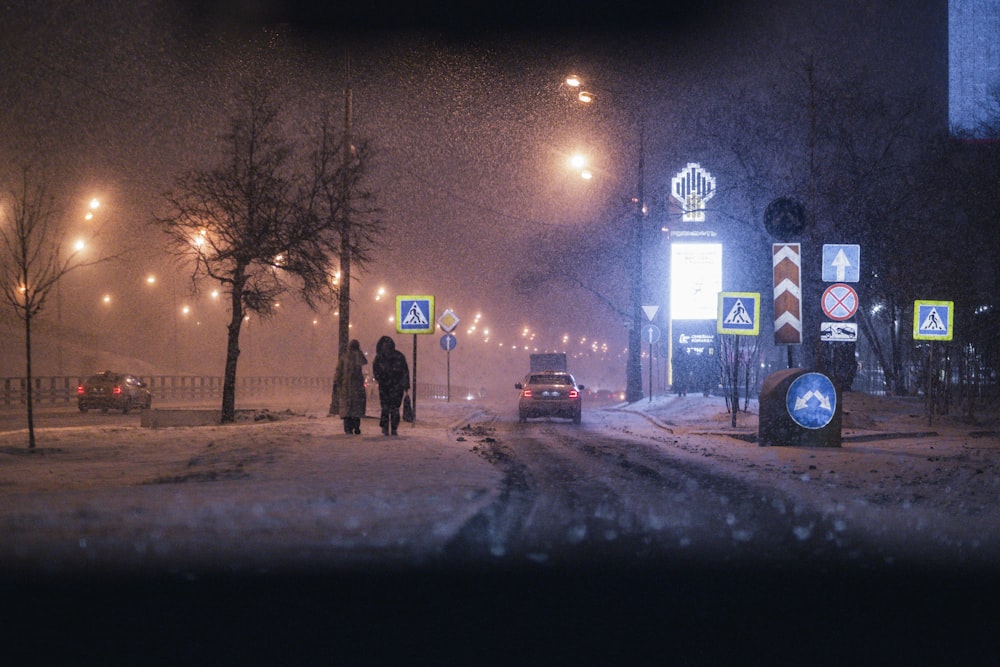 a couple of people walking down a snow covered street
