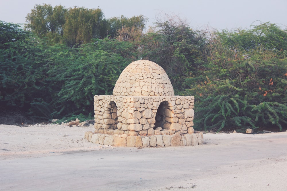 a stone oven sitting in the middle of a dirt road