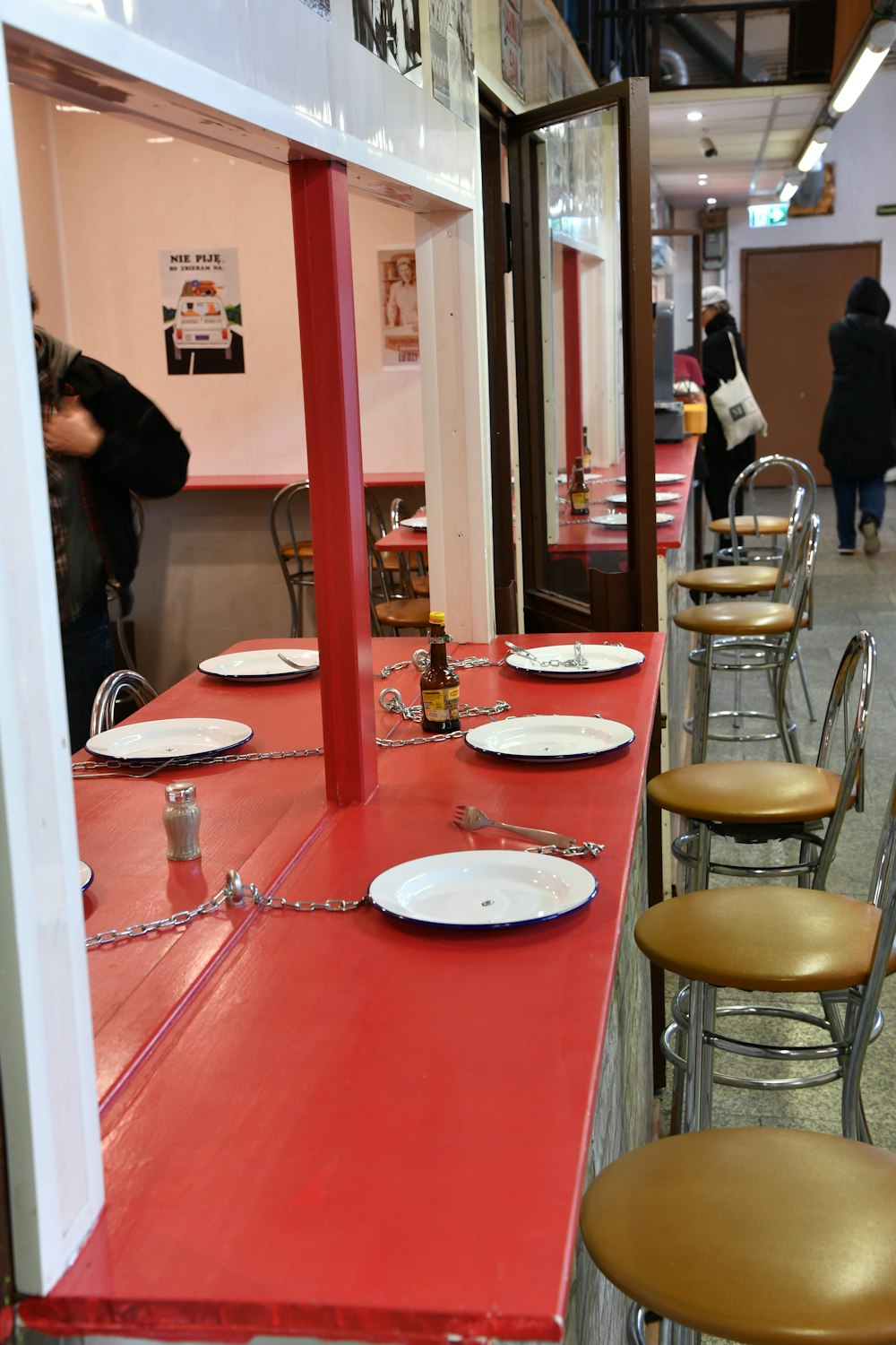 una larga mesa roja con platos blancos